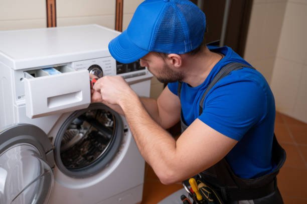 worker repairing washing machine in laundry room.